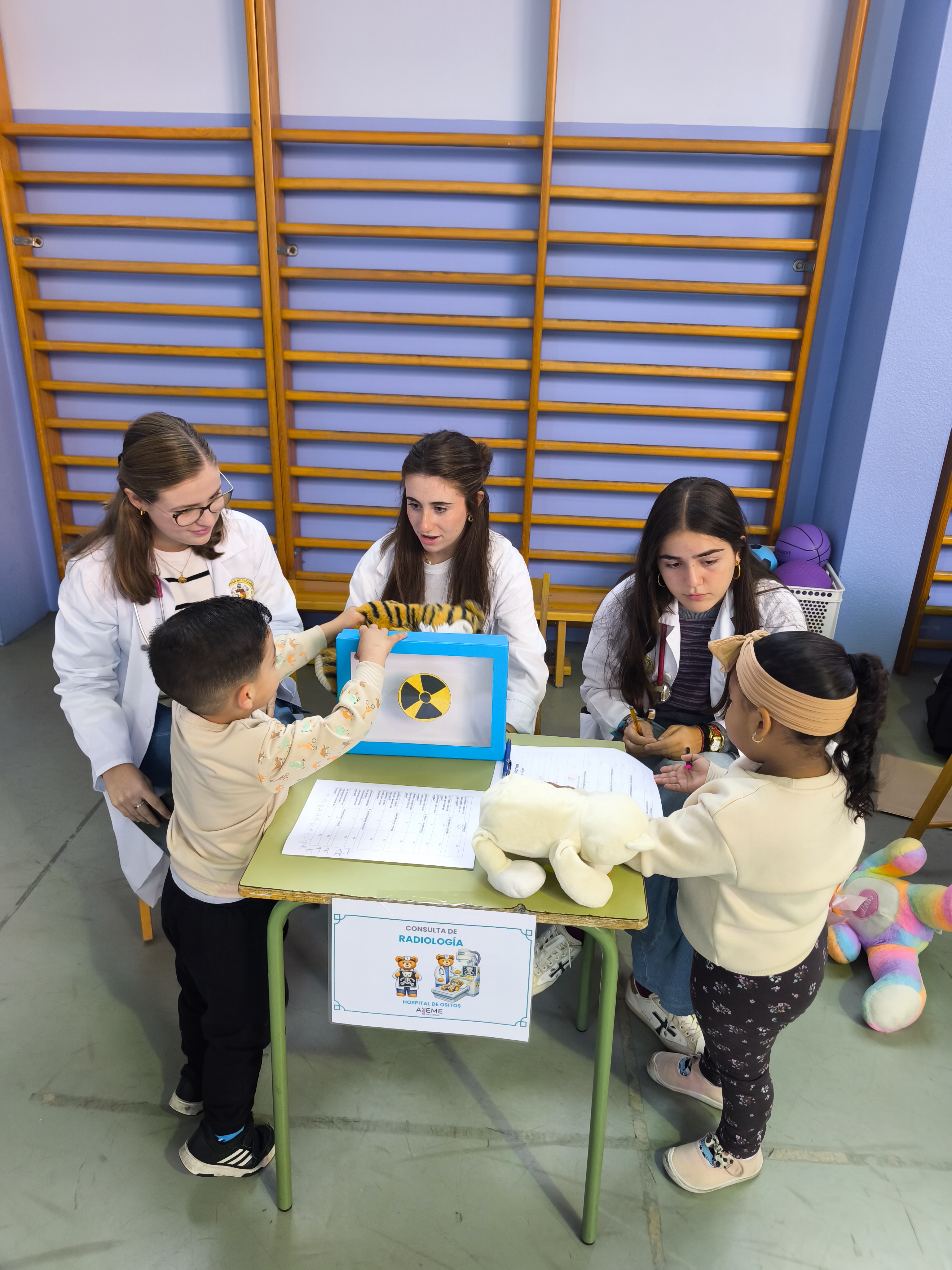 Niños participan con sus peluches en una consulta de radiología simulada junto a estudiantes
